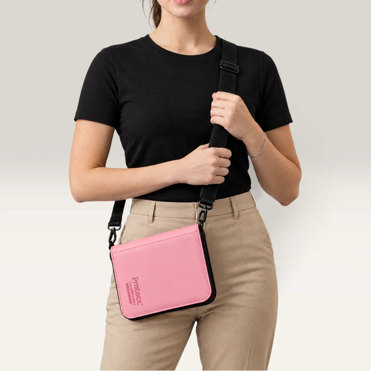 Pikaversum Protecc Guardium One Binder in Blush Pink, getragen als Umhängetasche mit schwarzem Tragegurt